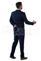 Rear view of businessman with fingers crossed extending arm for handshake