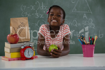 Schoolgirl holding a green apple against green background