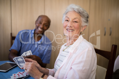 Portrait of senior woman playing cards with friend