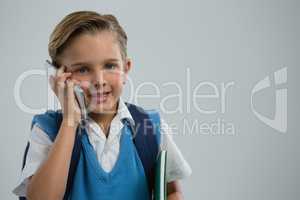 Portrait of happy schoolboy talking on mobile phone