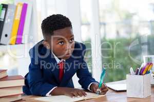 Businessman looking away while writing on book