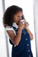 Businesswoman with curly having coffee while standing by window