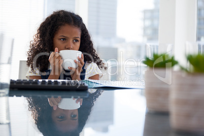 Thoughtful businesswoman having coffee while sitting at desk