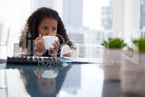 Thoughtful businesswoman having coffee while sitting at desk