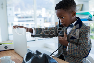 Businessman talking on telephone while touching laptop