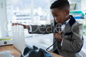 Businessman talking on telephone while touching laptop