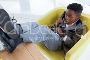 High angle view of boy imitating as businessman talking on landline phone