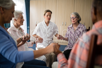 Female doctor meditating while holding hands with seniors