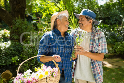 Senior couple walking in garden with flower basket