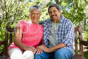 Portrait of senior couple sitting with arm around in garden