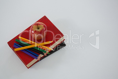 Apple and color pencil on book on white background