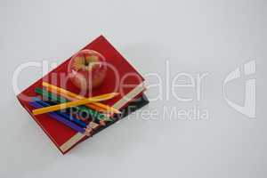 Apple and color pencil on book on white background