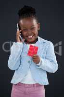 Portrait of cheerful businesswoman talking on phone while holding red card