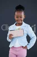 Portrait of smiling businesswoman with hand on hip holding paper currency