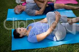 Smiling trainer exercising while lying down with senior people