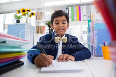 Smiling boy imitating as businessman writing on paper