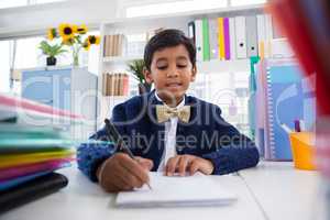 Smiling boy imitating as businessman writing on paper