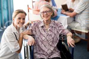 Portrait of smiling female doctor with disabled senior woman sitting on wheelchair