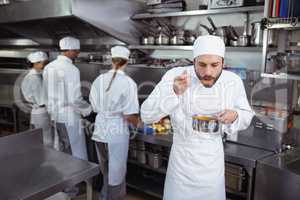 Chef tasting food from spoon in kitchen