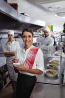 Waitress standing with kitchen staff in commercial kitchen