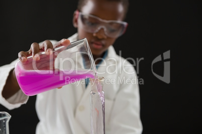 Schoolgirl doing a chemical experiment against black background