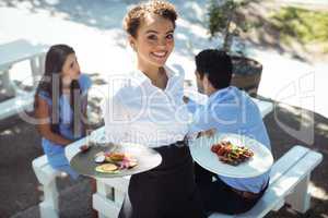 Smiling waitress holding delicious food in kitchen