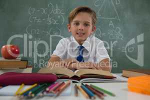 Schoolboy reading book in classroom