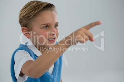 Schoolboy pointing finger against white background