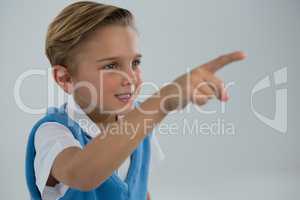 Schoolboy pointing finger against white background
