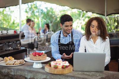 Male waiter and female waitress with laptop