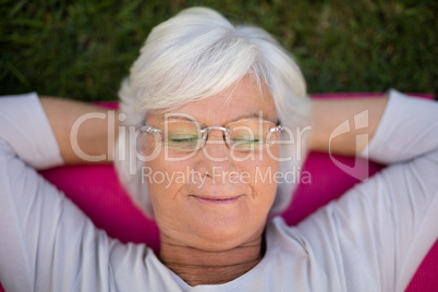 Senior woman resting with closed eyes on exercise mat