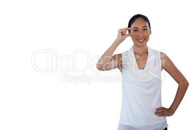 Portrait of smiling woman with hand on hip adjusting invisible eyeglasses