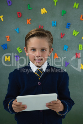 Schoolboy holding digital tablet against chalkboard