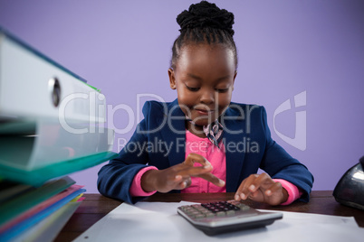 Businesswoman using calculator while doing paperwork