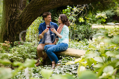 Romantic couple toasting a glass of red wine in garden