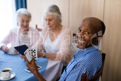 Portrait of smiling man playing cards with friends