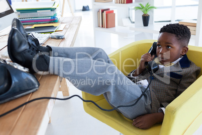 Full length of boy imitating as businessman talking on landline phone