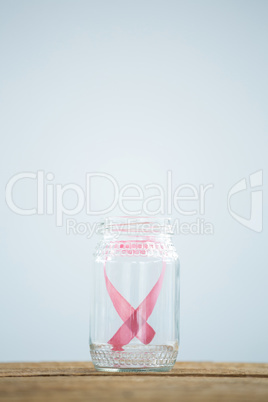 Close-up of pink Breast Cancer Awareness ribbon in glass jar on table