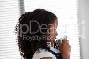 Side view businesswoman having coffee while standing by window