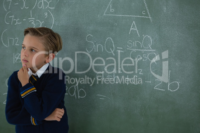 Schoolboy standing against chalkboard