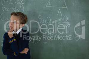 Schoolboy standing against chalkboard