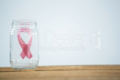 Close-up of pink Breast Cancer Awareness ribbon in glass jar