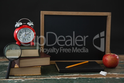 Stack of books with various stationery and apple