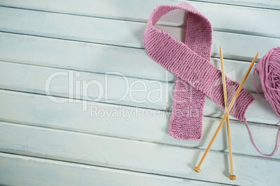 Overhead view of pink woolen Breast Cancer Awareness ribbon with crochet needles