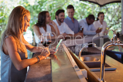 Smiling woman using mobile phone while having a glass of wine