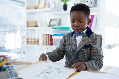 Confident businessman reading documents while sitting at desk