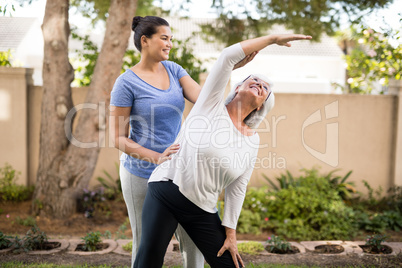 Smiling trainer instructing senior woman while exercising
