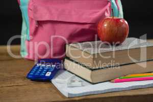 Schoolbag, supplies and apple on wooden table