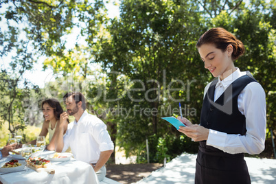 Smiling waiter writing order on notepad