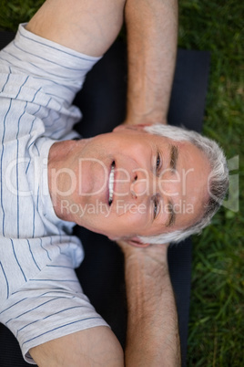 Portrait of smiling senior man resting while lying on exercise mat